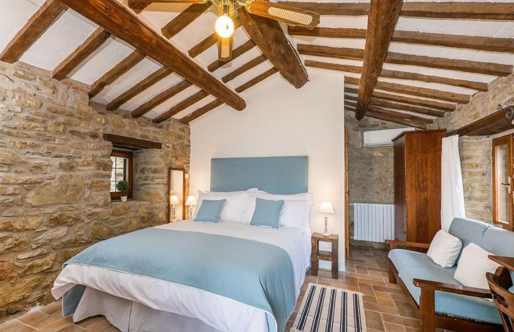 une chambre avec un grand lit et un mur en pierre dans l'établissement Villa Rinaldo by MMega, à Santa Cristina