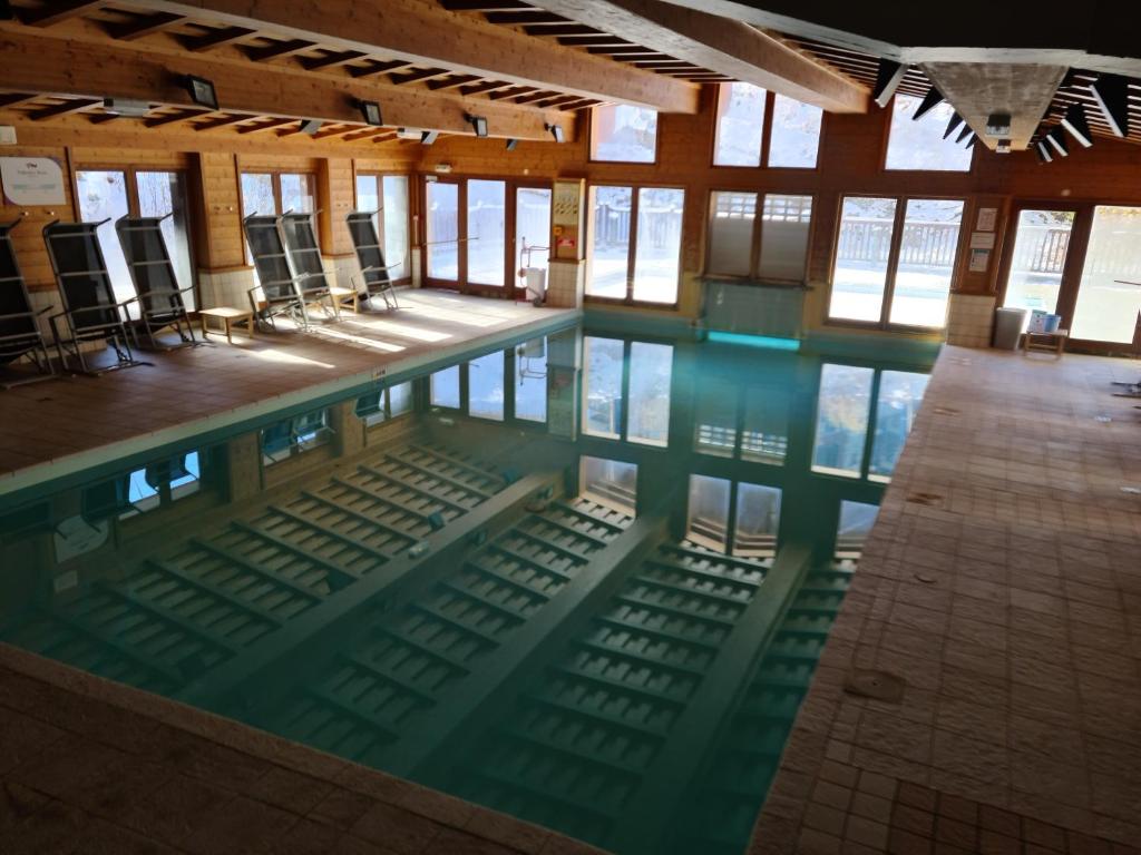 une piscine avec des chaises dans un immeuble dans l'établissement Arc 1950 Appartement de standing Refuge du Montagnard, vue incroyable sur le Montblanc, skis aux pieds Accès spa et piscine, à Arc 1950