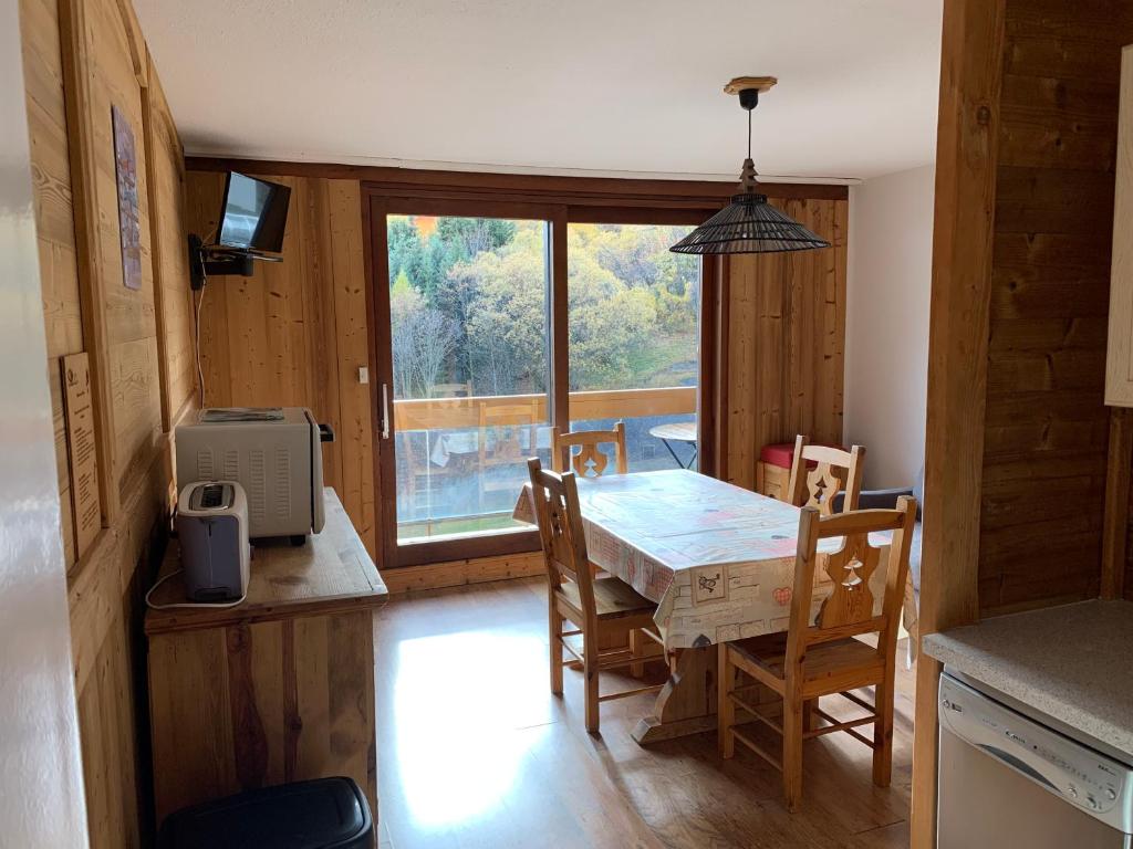 une cuisine et une salle à manger avec une table et une fenêtre dans l'établissement T2 vue piste Résidence Vostok Zodiaque, au Corbier