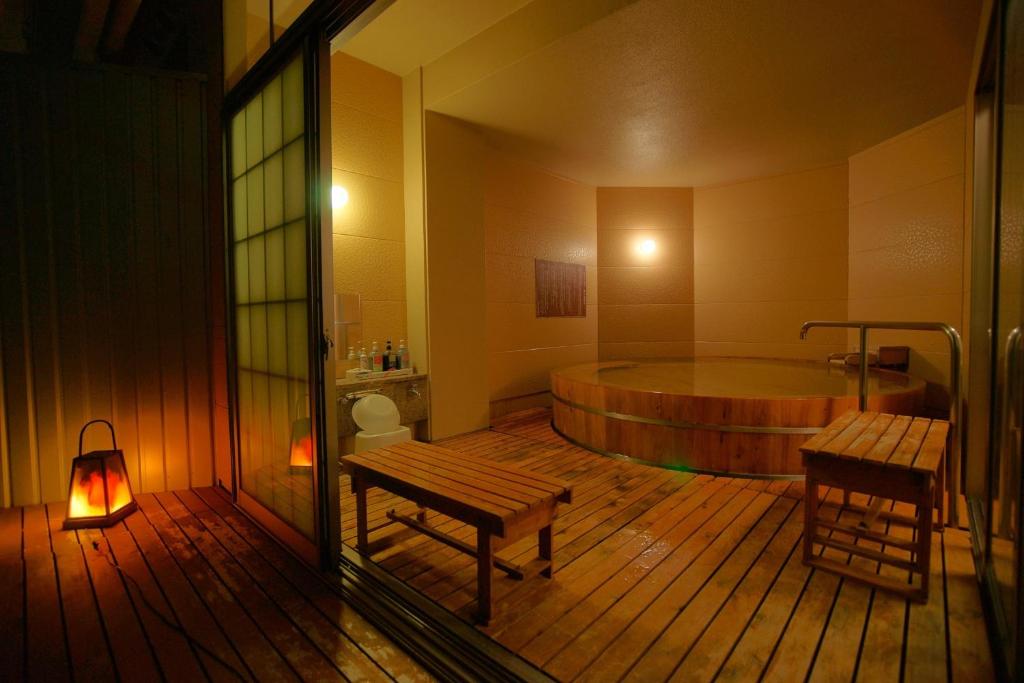 La salle de bains est pourvue d'une baignoire, d'un banc et d'une table. dans l'établissement Hotel Kaminoyu Onsen, à Kai