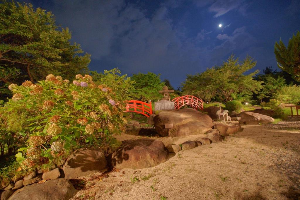 un jardin avec des rochers, des arbres et une lune dans l'établissement Hotel Kaminoyu Onsen, à Kai