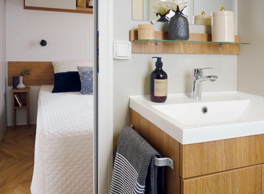 une petite salle de bain avec un lavabo et un lit dans l'établissement Évasion Lodge, à Gastes
