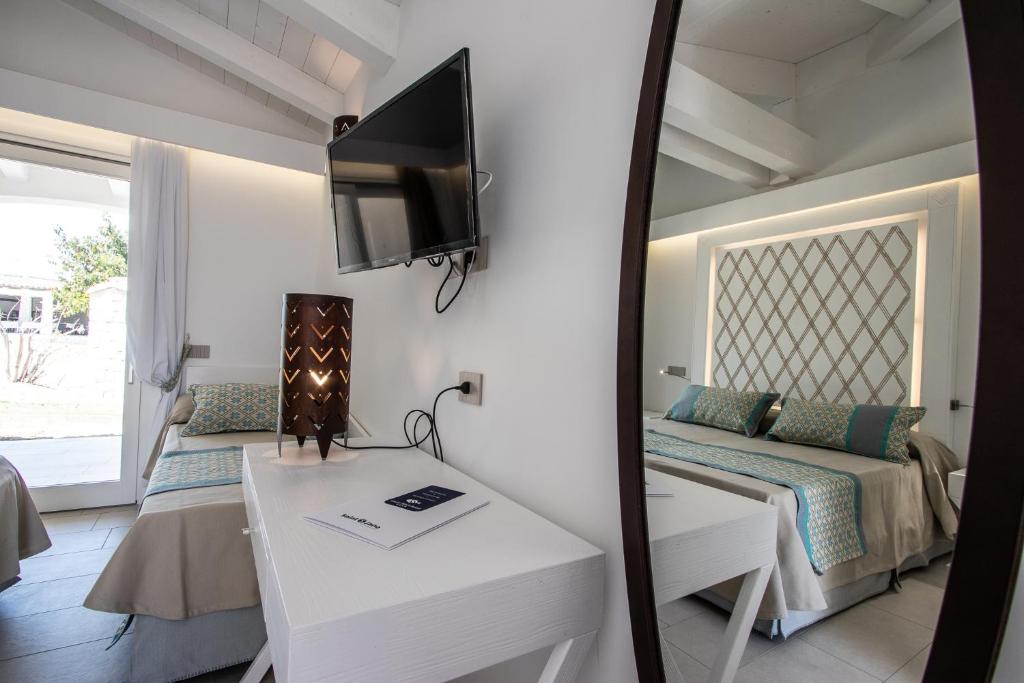 une petite chambre avec un lit et un miroir dans l'établissement Limone Beach Resort, à Castiadas