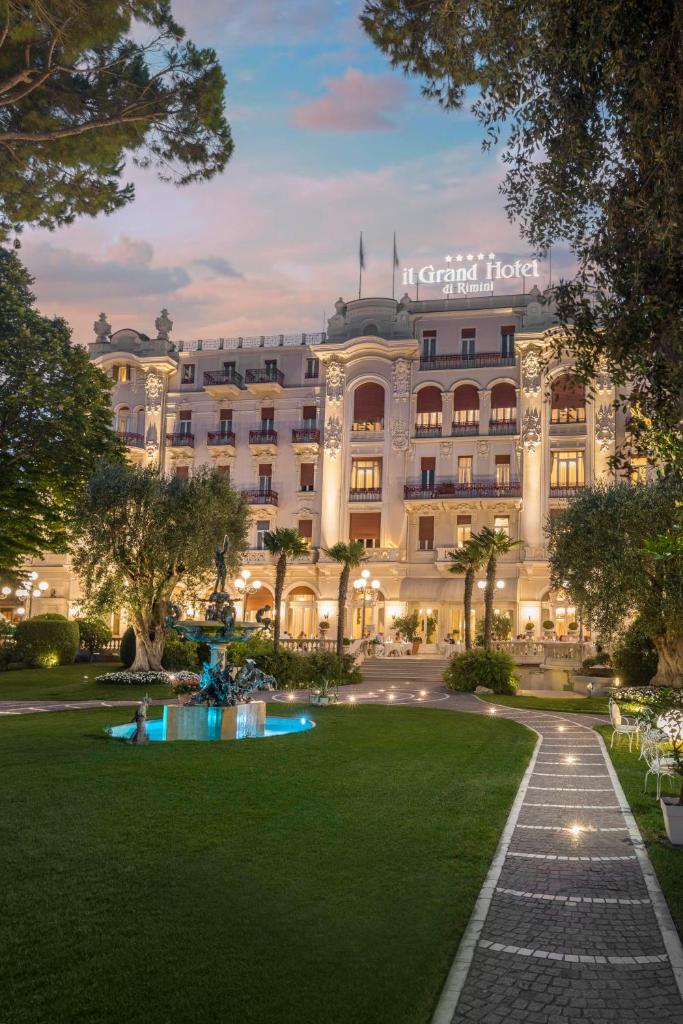 un grand bâtiment avec une pelouse devant dans l'établissement Grand Hotel Rimini, à Rimini