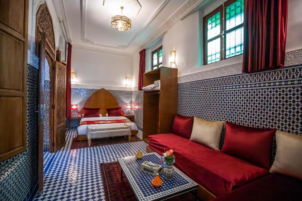 - un salon avec un canapé rouge et un lit dans l'établissement Riad Dilar Fes & Spa, à Fès