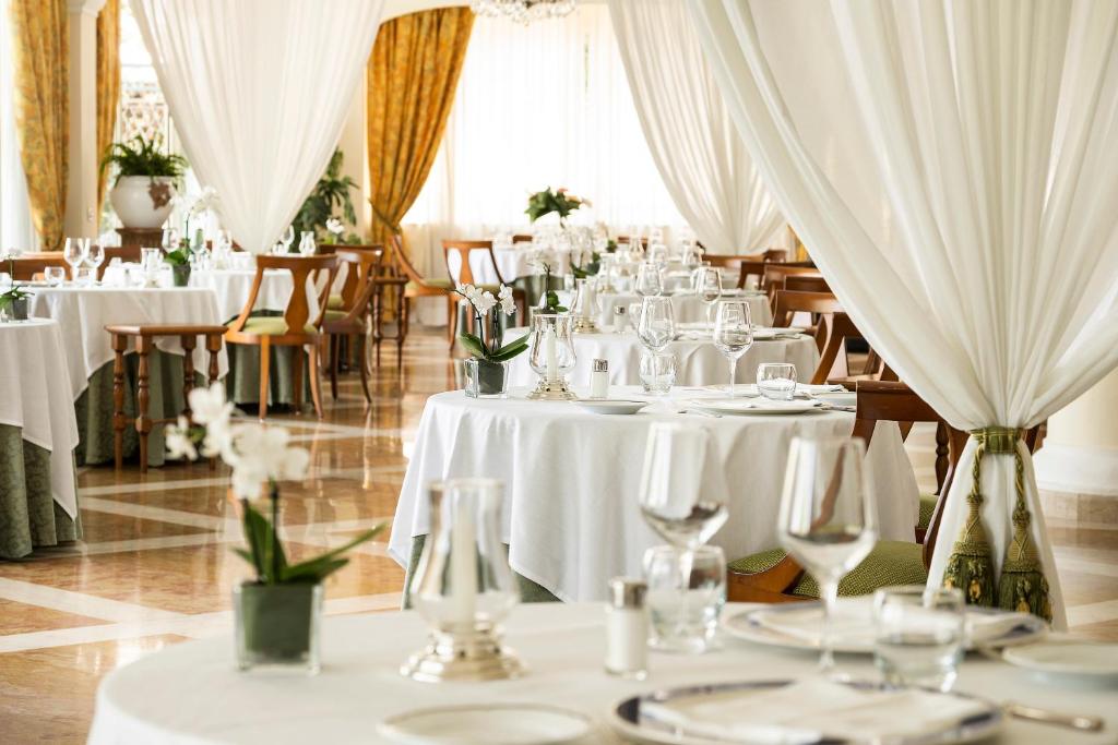 une salle à manger avec des tables et des chaises blanches dans l'établissement Excelsior Belvedere Hotel & Spa, à Ischia 50 autres photos