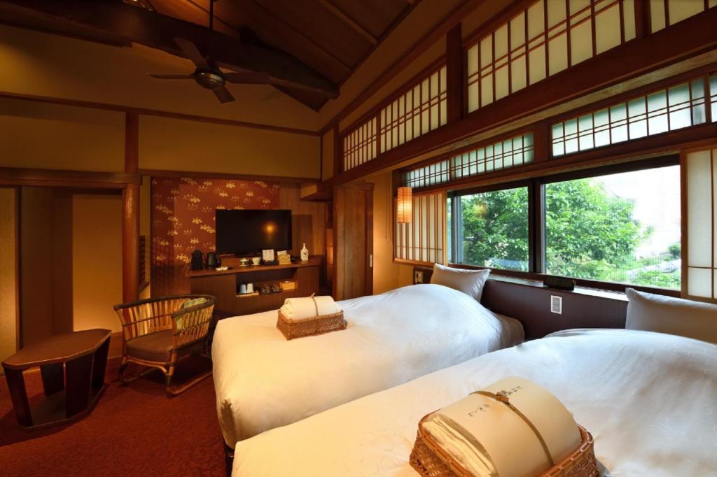 - une chambre avec 2 lits, une télévision et une fenêtre dans l'établissement Muromachi Yutone Kyokoyado, à Kyoto