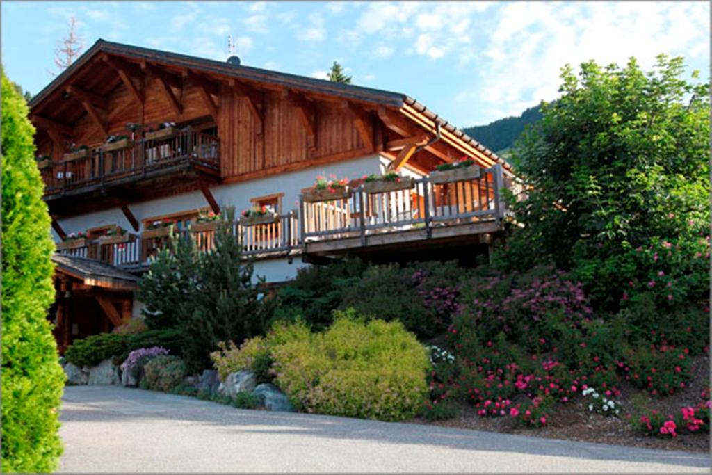 Cette grande maison en bois dispose d'un balcon et de fleurs. dans l'établissement Hôtel La Ferme du Chozal, Chalet de tradition, à Hauteluce