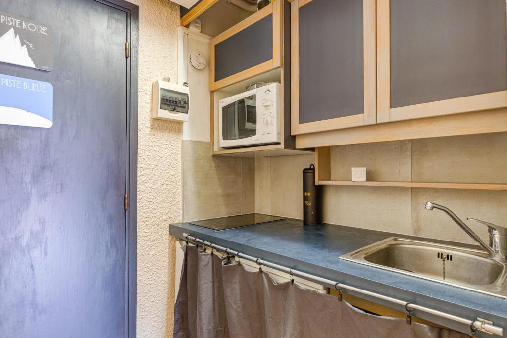 une cuisine avec un évier et un micro-ondes dans l'établissement Sunny studio with balcony, à La Clusaz