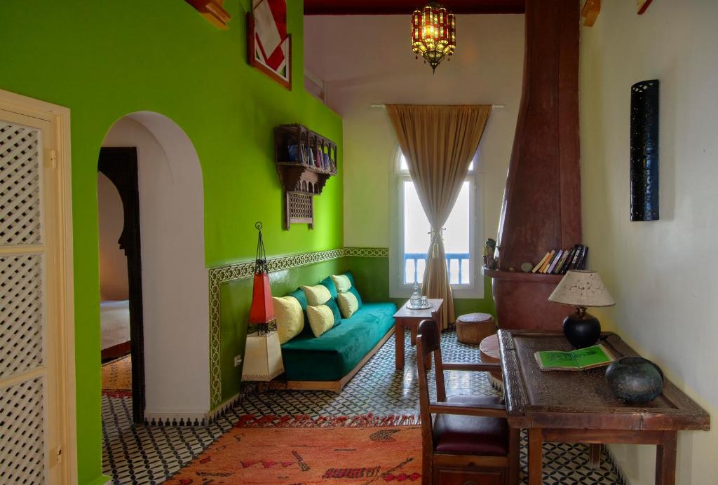 - un salon avec des murs verts et un canapé bleu dans l'établissement Ryad Watier & SPA, à Essaouira