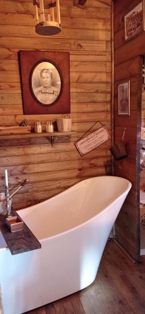 une salle de bains avec baignoire et une photo d'un homme dans l'établissement Cabanes Nature Morvan, à Blanot 9 autres photos