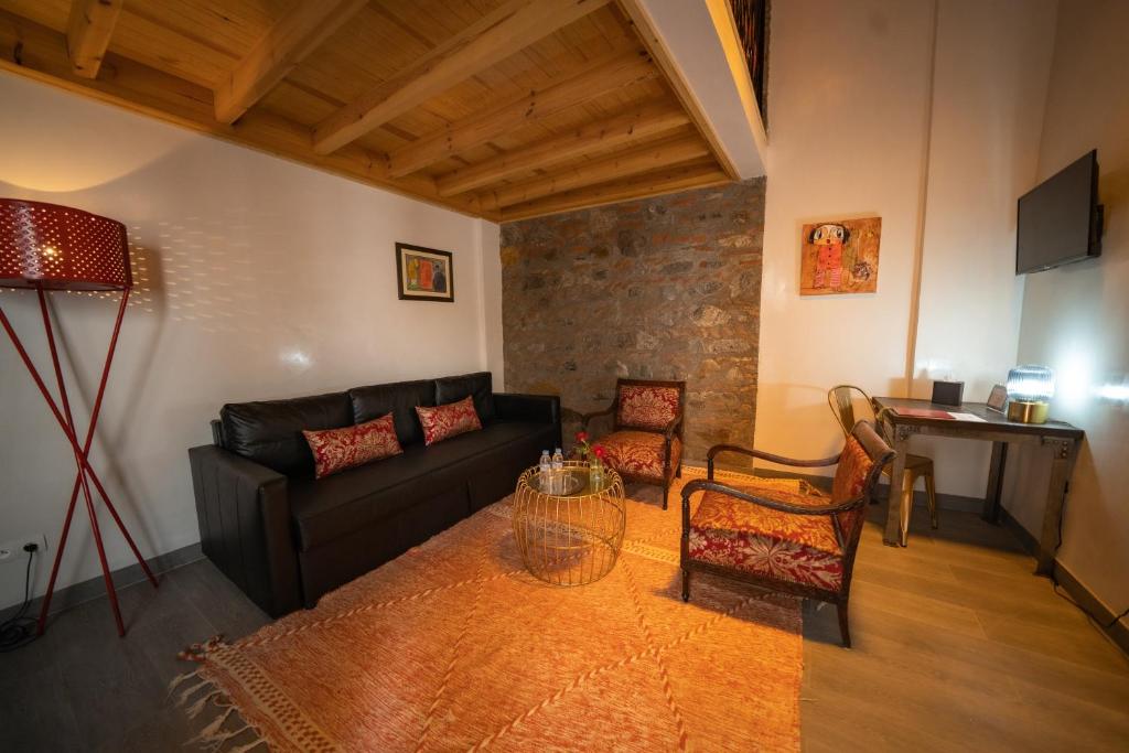 - un salon avec un canapé noir et deux chaises dans l'établissement Riad Shanima SPA Marrakech, à Marrakech