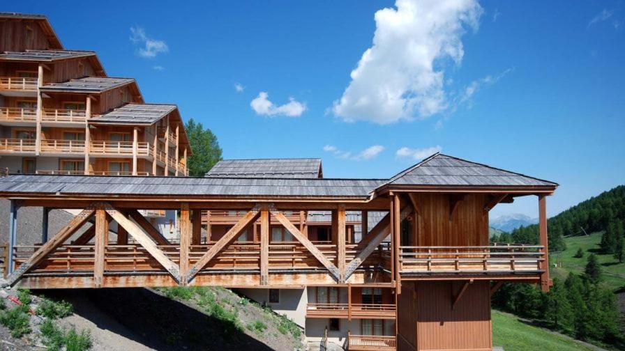 un bâtiment avec un pont en bois dans les montagnes dans l'établissement Appt Le Hameau Des Rennes 4 étoiles Pieds des pistes Piscine Intérieure Extérieure, à Vars