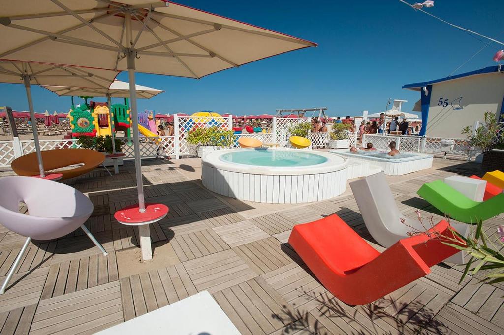une terrasse avec un bain à remous, des chaises et un parasol dans l'établissement Hotel Giulio Cesare, à Rimini