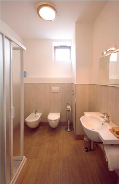 une salle de bain avec deux lavabos et un WC dans l'établissement Hotel Giulio Cesare, à Rimini