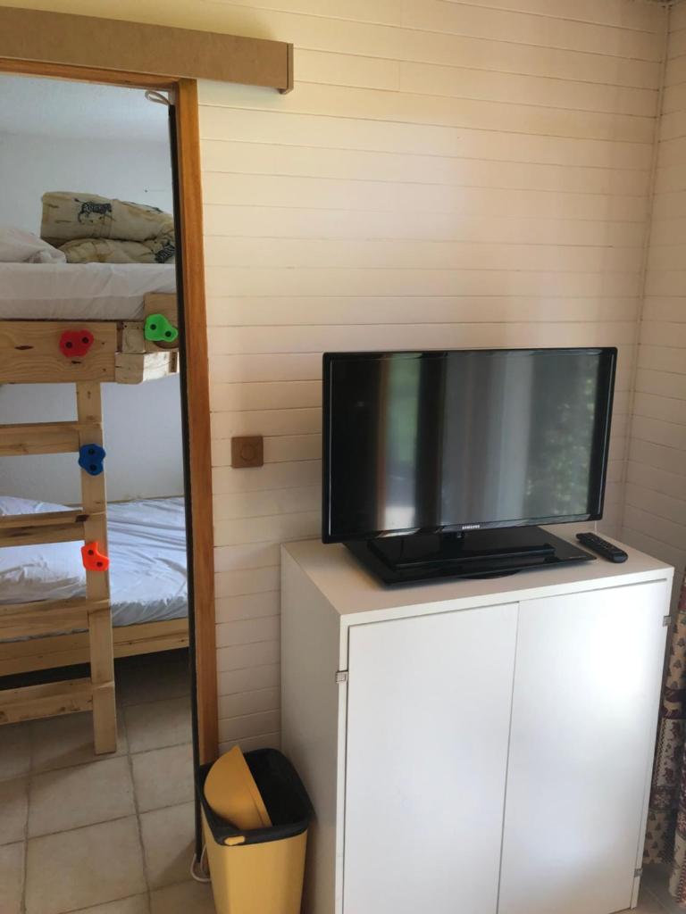 - une télévision sur une commode dans une chambre avec des lits superposés dans l'établissement Appartement 2 pièces pieds des pistes terrasse face à la montagne, à Bernex
