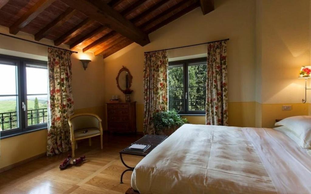 une chambre avec un grand lit et deux fenêtres dans l'établissement Villa Santa Virginia by Halldis, à Montaione