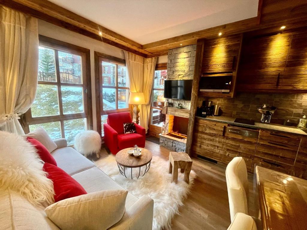 un salon avec un canapé blanc et une chaise rouge dans l'établissement Arc 1950 appt luxe 2-4pers -skis aux pieds-SPA-piscines intérieure et extérieure-sauna-hammam, à Arc 1950