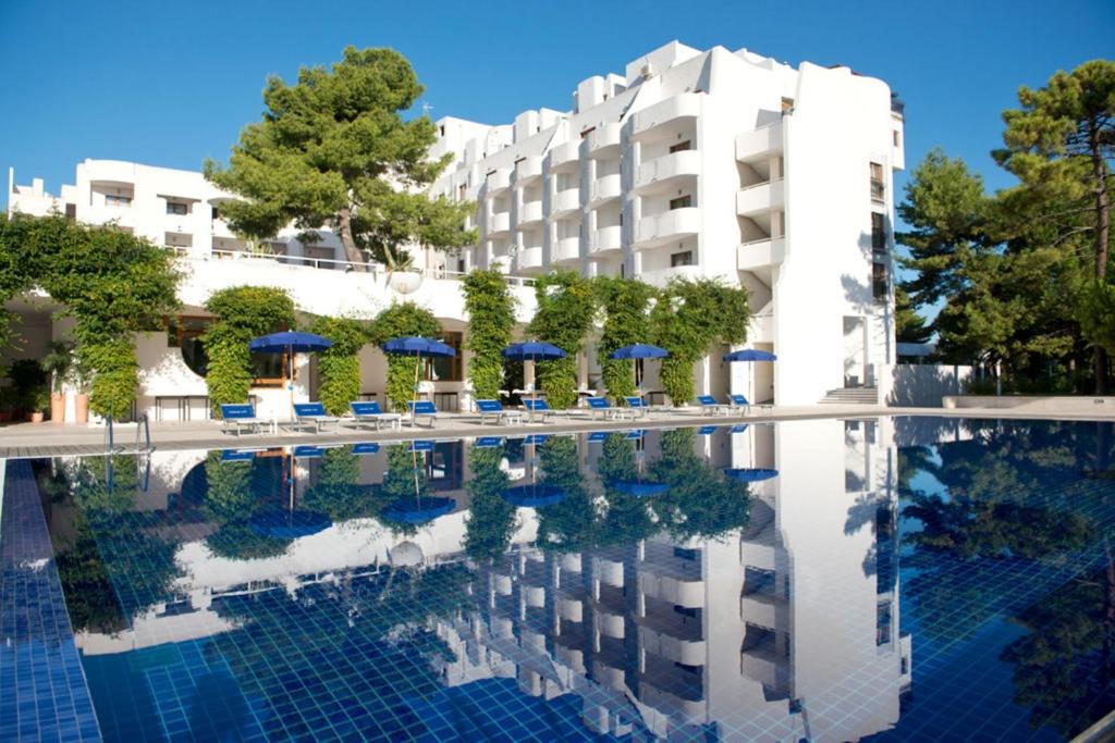 un hôtel avec une piscine devant un immeuble dans l'établissement Pizzomunno Vieste Palace Hotel, à Vieste