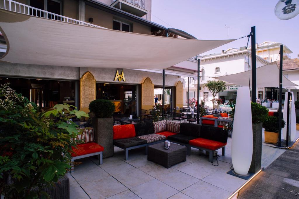 une terrasse avec des canapés et des parasols devant un restaurant dans l'établissement Hotel Margherita, à Lido di Jesolo