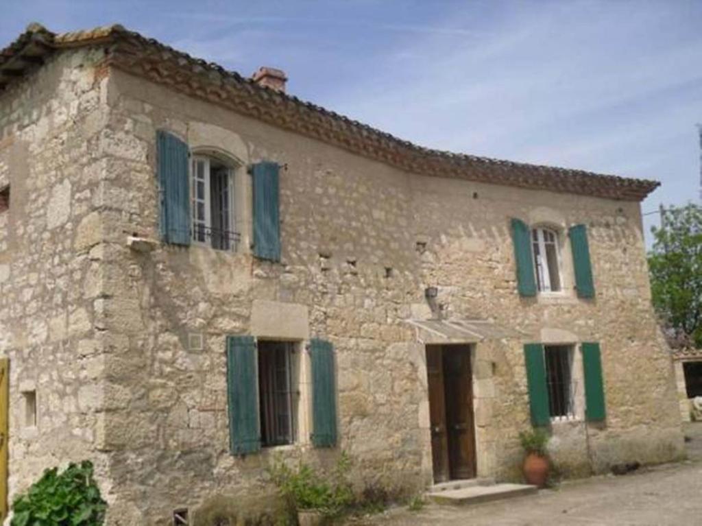 - un vieux bâtiment en pierre avec des volets verts dans l'établissement Les gîtes de Franck, à Fayssac
