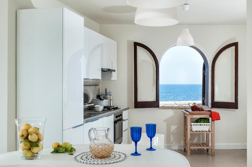 - une cuisine avec 2 fenêtres et une table avec des fruits dans l'établissement Marina dei Greci - Luxury Villa, à Giardini Naxos