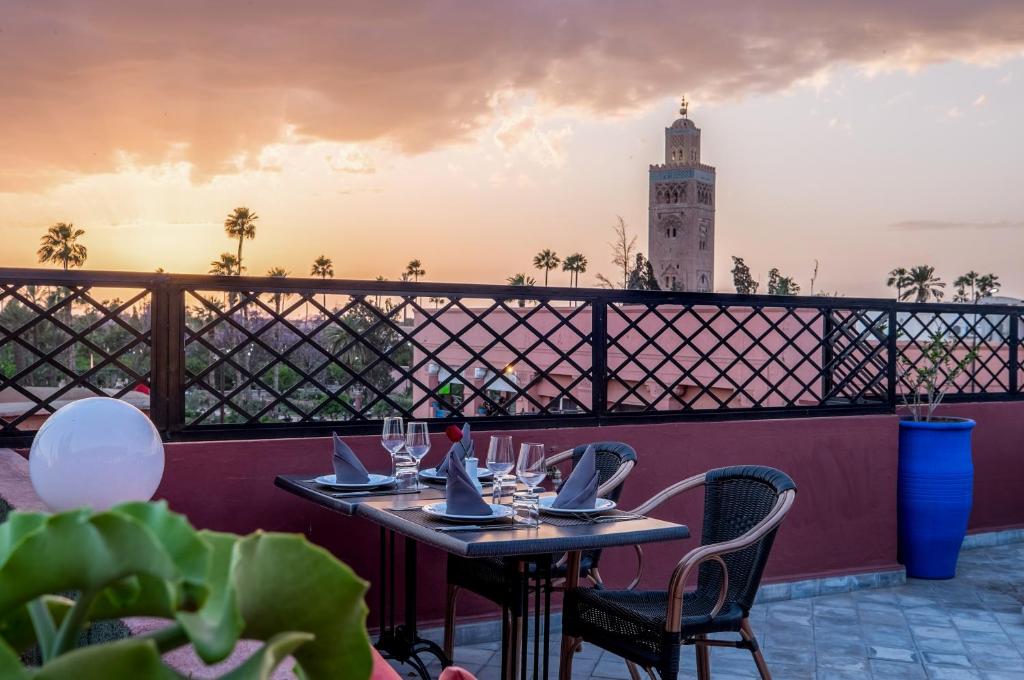 d'une table et de chaises sur un balcon avec une tour d'horloge. dans l'établissement Riad Marrakech By Hivernage, à Marrakech