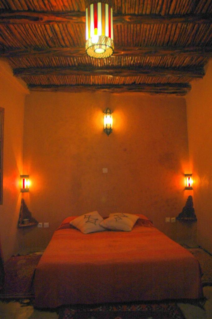 - une chambre avec un lit et deux lumières sur le mur dans l'établissement Riad Jade Mogador, à Essaouira