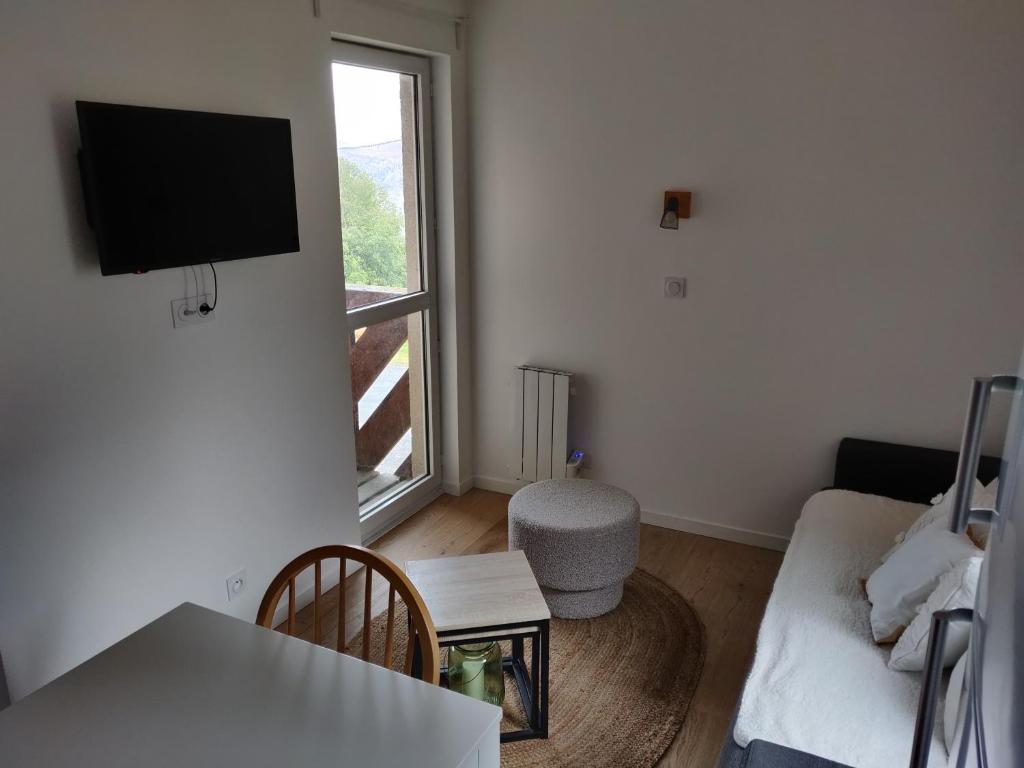un salon avec un canapé et une télévision au mur dans l'établissement Appartement neuf 4-6 pers. aux pieds des pistes, à Génos