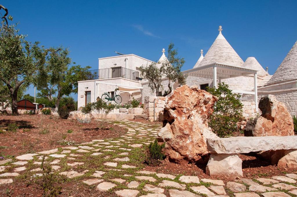 une grande maison blanche avec un chemin en pierre devant elle dans l'établissement Trulli Loco, à Locorotondo