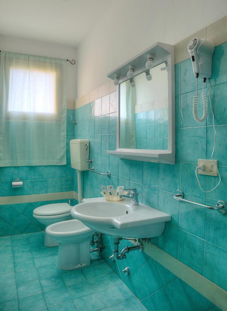 une salle de bain bleue avec un lavabo et des toilettes dans l'établissement Hotel AMALFI, à Lido di Jesolo