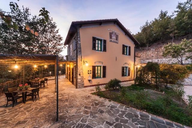 un bâtiment avec une table et des chaises devant lui dans l'établissement Agriturismo Le Meridiane, à Borgomaro