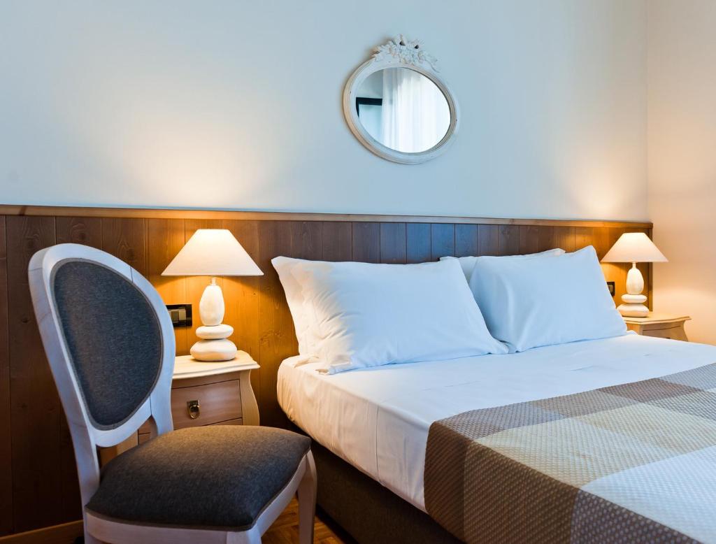 une chambre avec un lit, une chaise et un miroir dans l'établissement Hotel Ambassador, à Pesaro