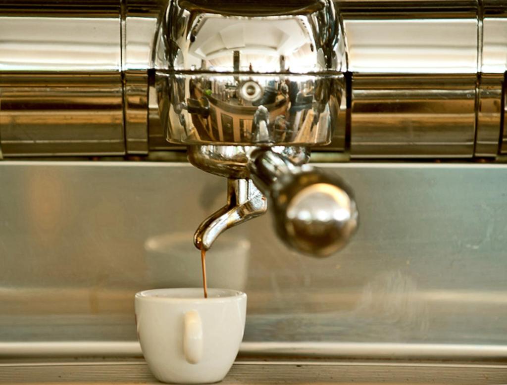 - une machine à café avec du café dans une tasse blanche dans l'établissement Hotel Ambassador, à Pesaro