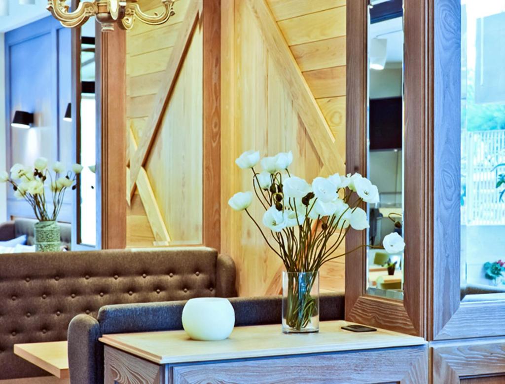 un vase de fleurs sur une table avec un miroir dans l'établissement Hotel Ambassador, à Pesaro