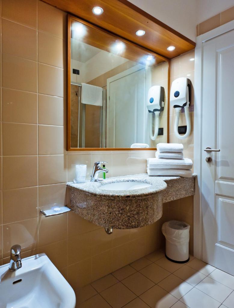 une salle de bain avec un lavabo et un miroir dans l'établissement Hotel Ambassador, à Pesaro 28 autres photos