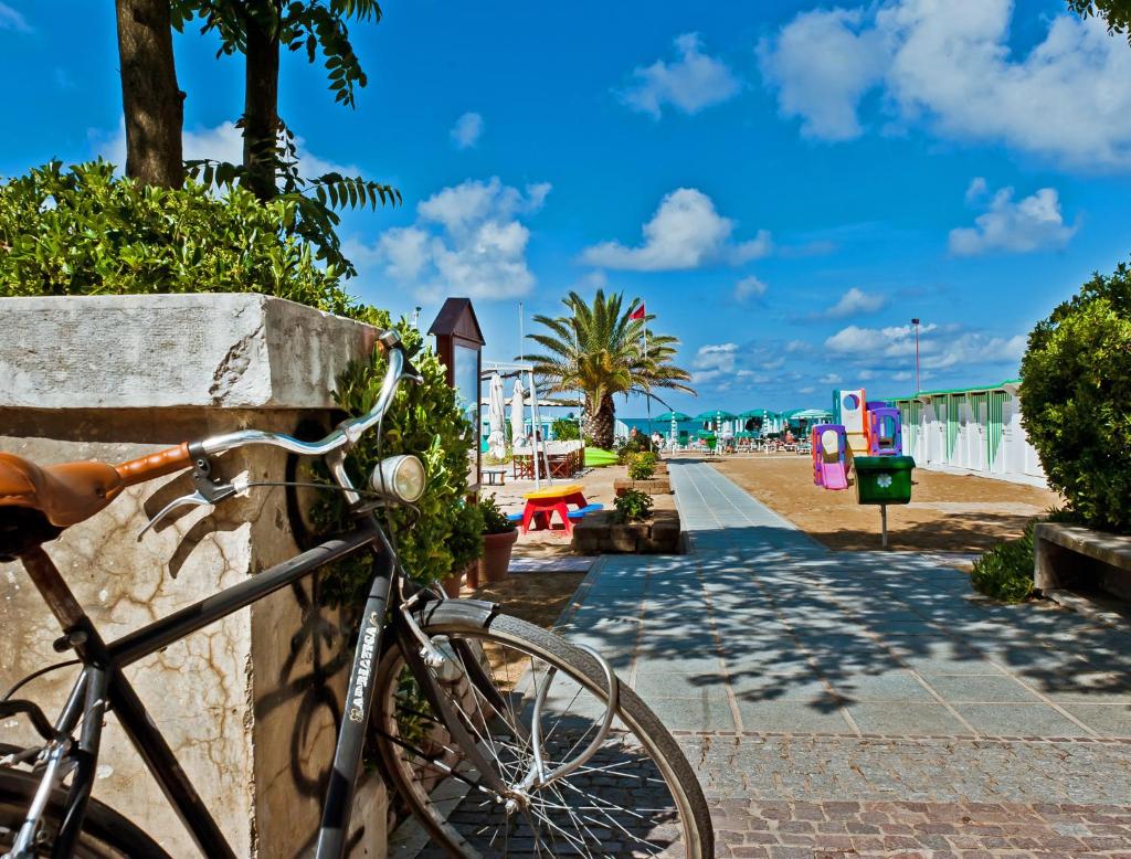 un vélo garé contre un mur en pierre à côté de la plage dans l'établissement Hotel Ambassador, à Pesaro