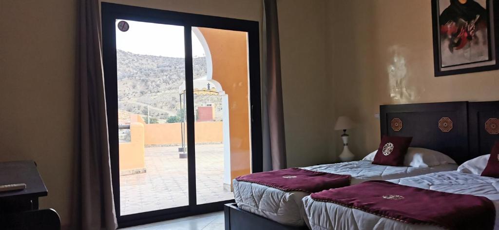 deux lits dans une chambre avec une grande fenêtre dans l'établissement Riad Asmaa Agadir, à Agadir