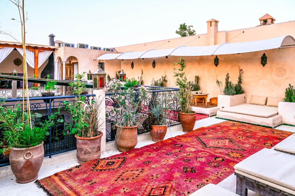 un patio avec des plantes et un tapis rouge dans l'établissement Riad Nouceiba Marrakech, à Marrakech