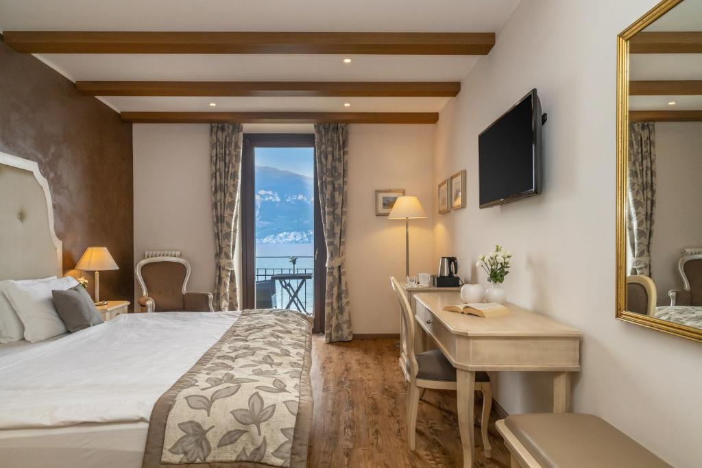 une chambre d'hôtel avec un lit, un bureau et une télévision dans l'établissement Lake Front Hotel Brenzone, à Brenzone
