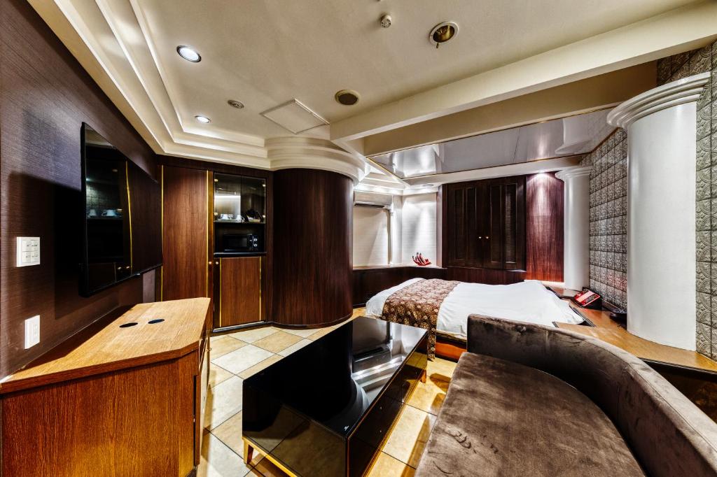 une chambre avec un lit et un bureau dans une pièce dans l'établissement HOTEL ARTIA DINOSAUR MACHIDA -Adult Only, à Kami-seya