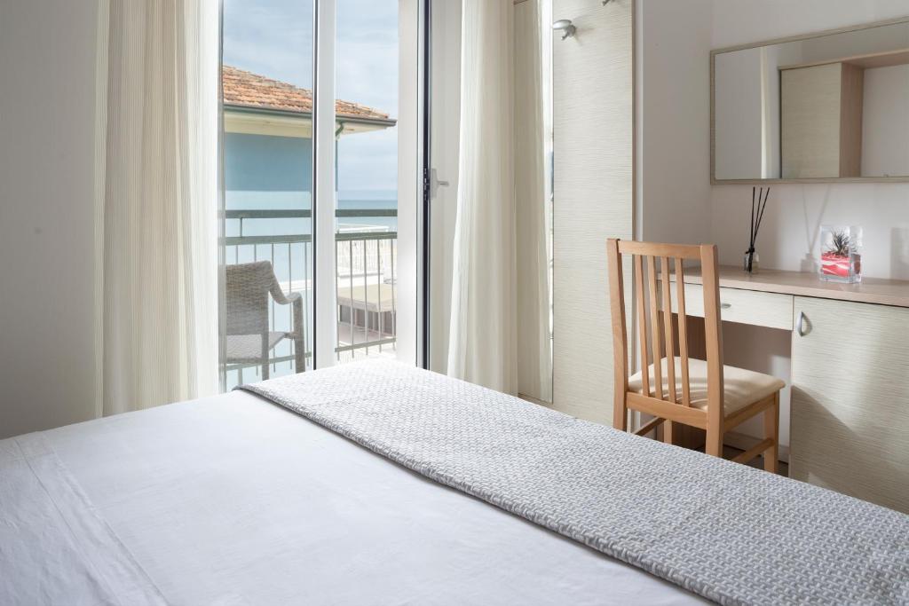 une chambre avec un lit et un bureau et un balcon dans l'établissement Hotel Riviera, à Bellaria-Igea Marina