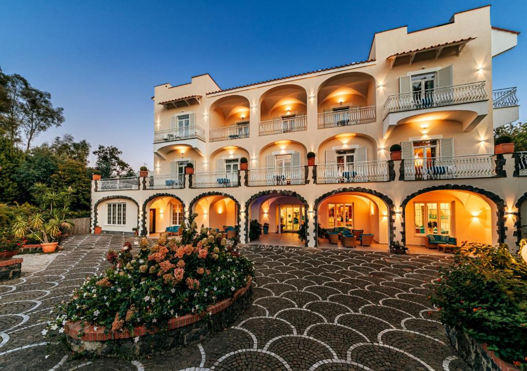 un grand bâtiment avec des fleurs dans une cour dans l'établissement Hotel Regina Palace Terme, à Ischia