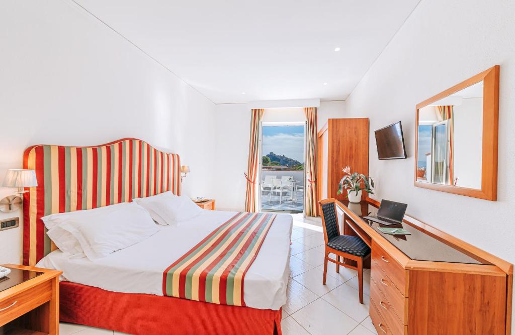une chambre d'hôtel avec un lit et un bureau avec un ordinateur portable dans l'établissement Hotel Regina Palace Terme, à Ischia
