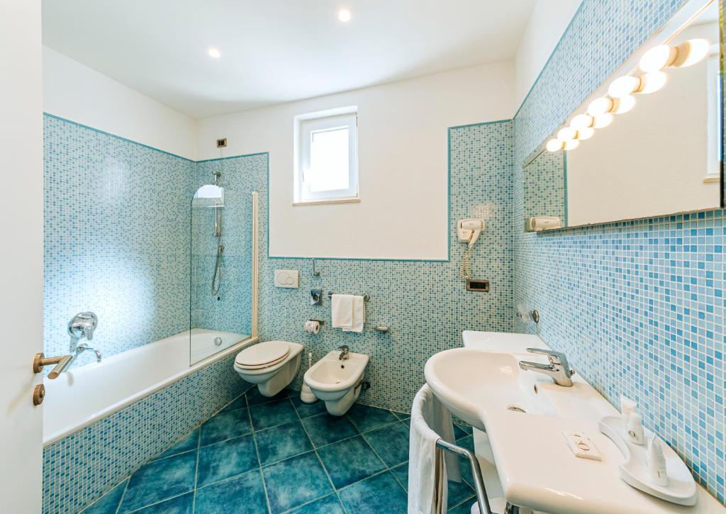 une salle de bain avec deux lavabos et une baignoire et des toilettes dans l'établissement Hotel Regina Palace Terme, à Ischia