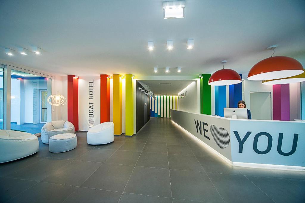 - un hall aux murs colorés et une femme assise sur un bureau dans l'établissement Love Boat Hotel - The Original, à Riccione
