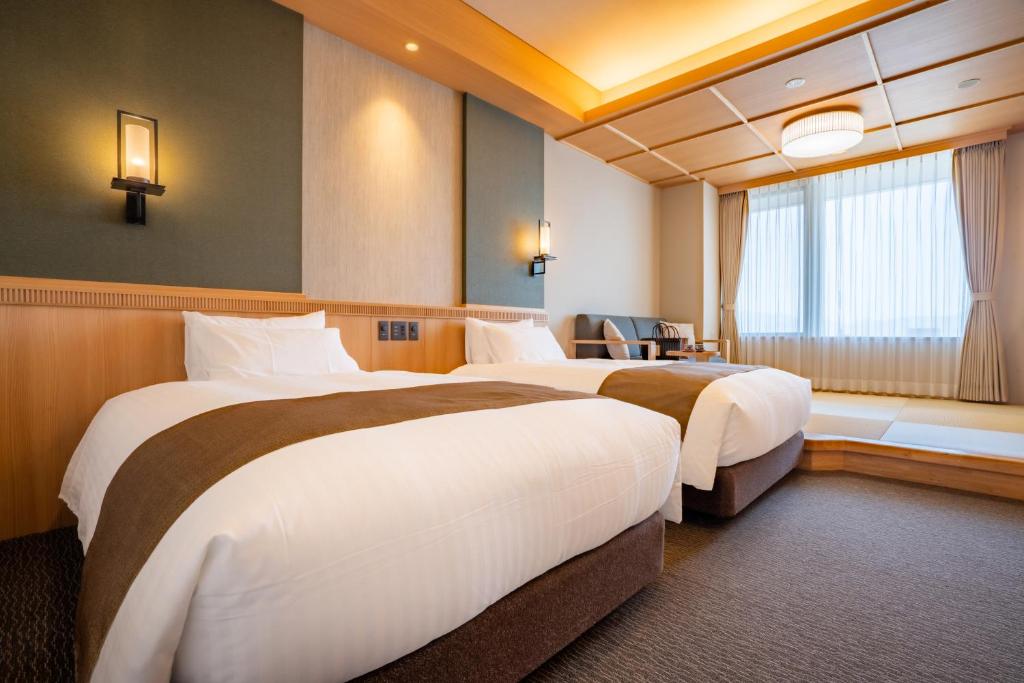 une chambre d'hôtel avec deux lits et une fenêtre dans l'établissement Kowakuen Haruka, à Matsuyama