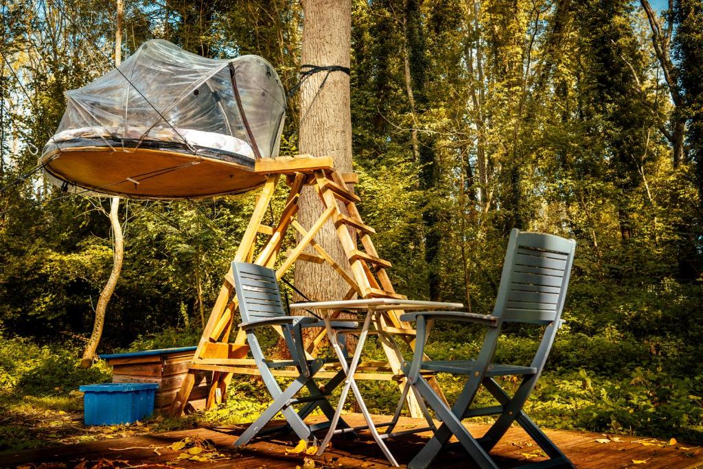 un bateau assis sur un support en bois à côté de deux chaises dans l'établissement Les Bulles de la Maison du Rocher, à Noisy-sur-École
