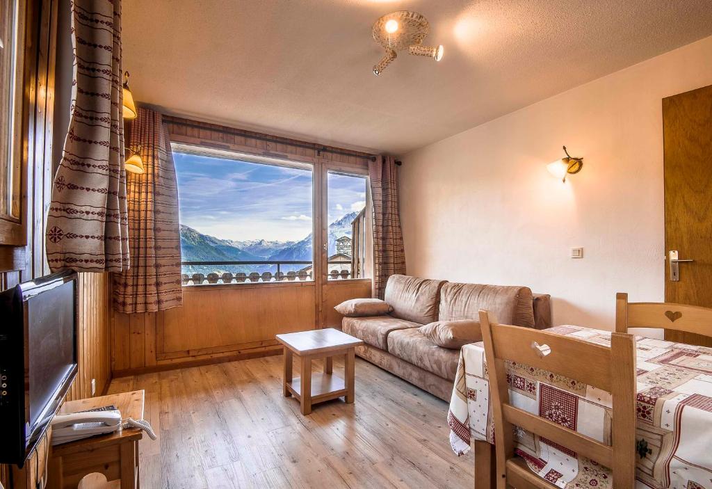 un salon avec un canapé et une grande fenêtre dans l'établissement Le Panoramic, à La Rosière