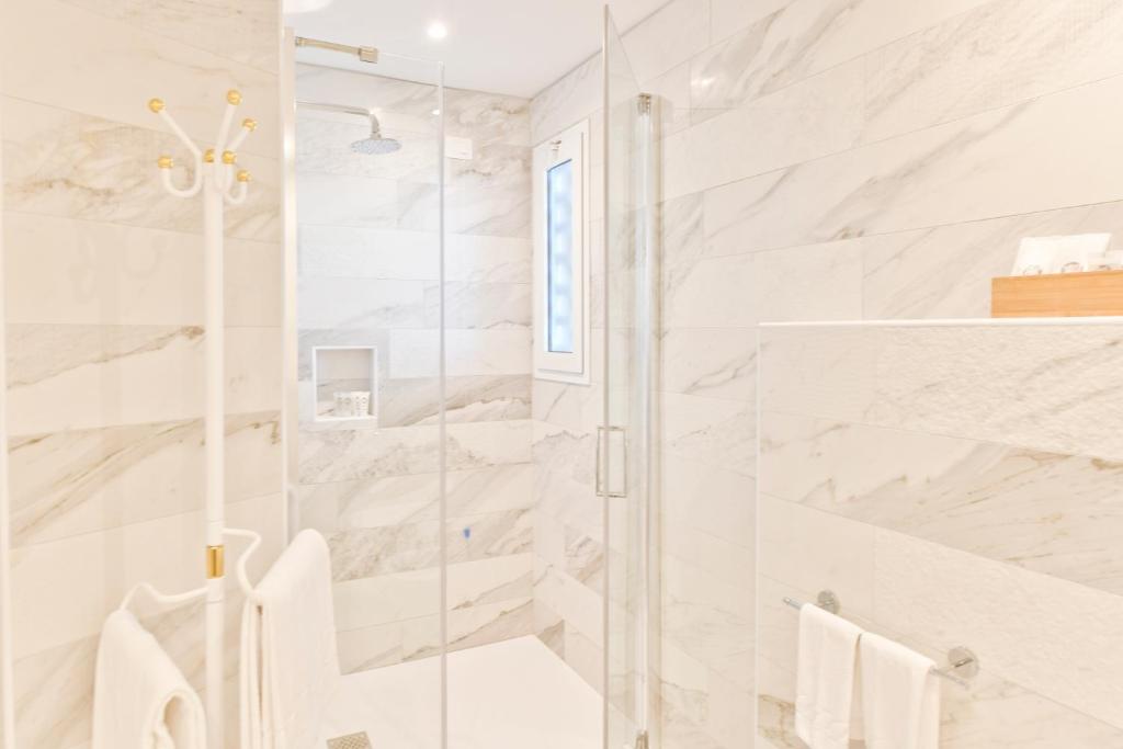 La salle de bains est pourvue d'une douche et de murs en marbre blanc. dans l'établissement Hotel Delle Nazioni, à Lido di Jesolo